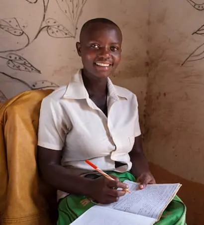 Amida Tuyishimire with her school books and pens for the education she is now able to receive because of the Graduation Programme at her home in Bukinanyana, Cibitoke, Burundi.