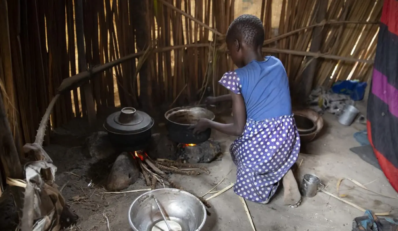 A young girl tends a cooking fire in South Sudan