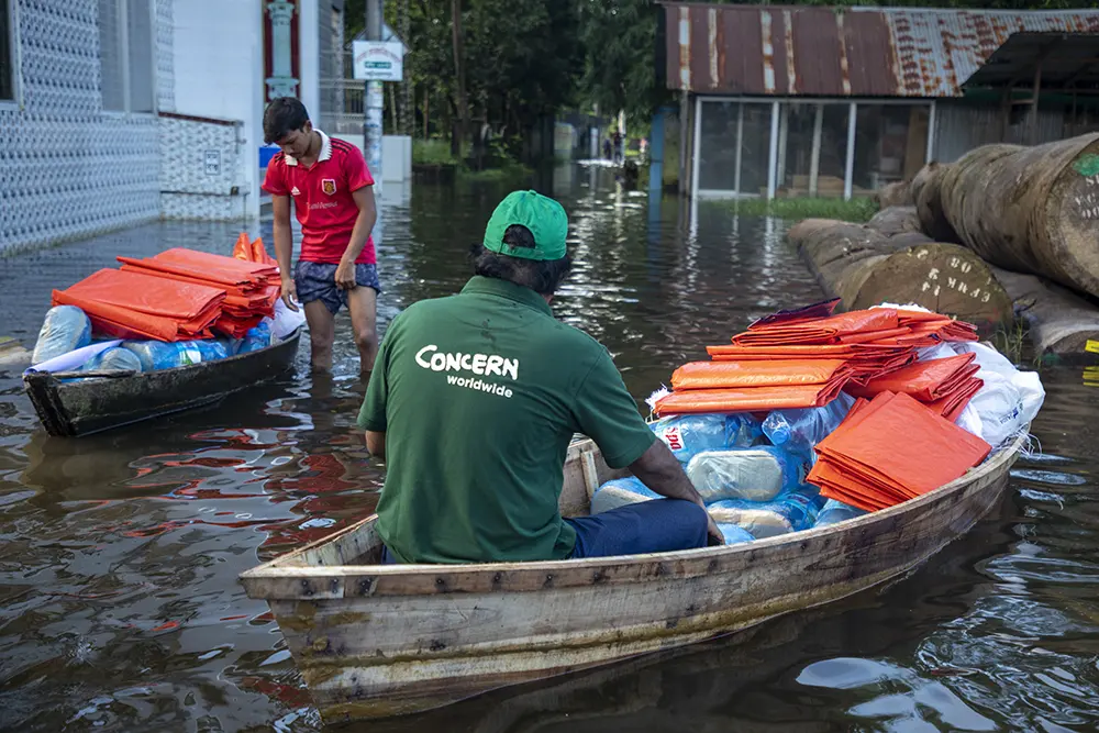 A Concern aid worker naviagtes a flood in Bangladesh