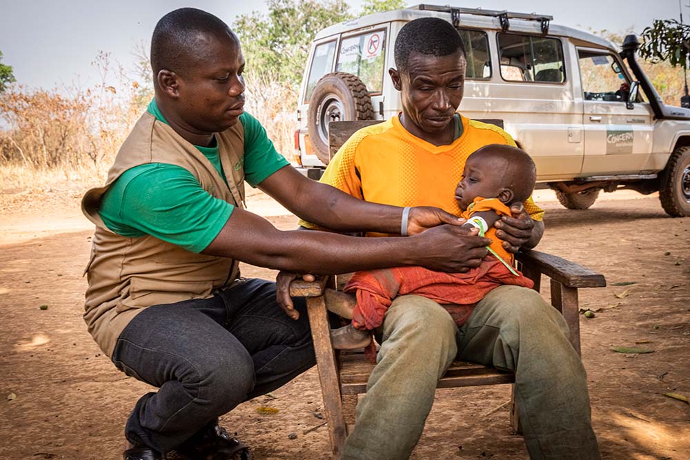 Guy Wanape with his son Sandrene Wanape in Ngata village receive a nutritional screening from a Concern community health worker. (Photo: Ed Ram / Concern Worldwide)