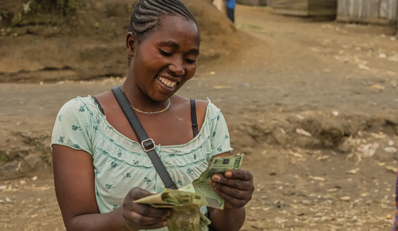 Consolata Sifa Bagenaimana counts her earnings after a day of selling cooking spices at the market. She is a participant in Concern's Graduation program in Burungu Kitshanga, DRC, which combines education and small-business resources. (Photo: Pamela Tulizo / Panos Pictures for Concern Worldwide)
