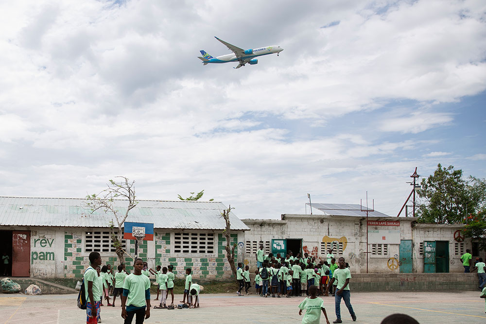 An airplane flies over a schoolyard in Port au Prince Haiti