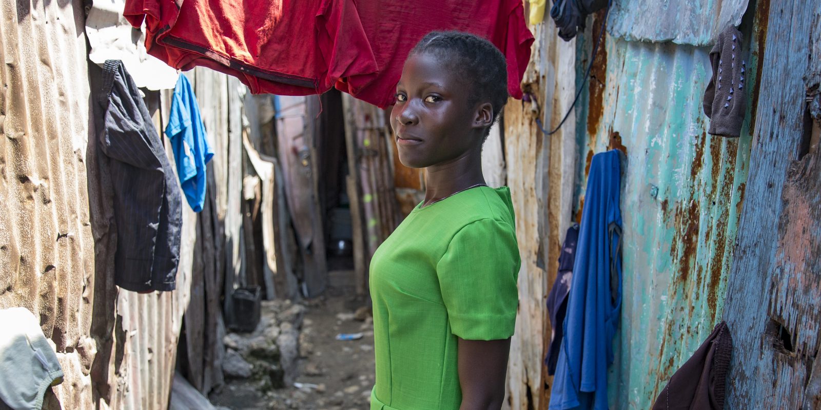 Émanise proudly wearing the lime green dress she tailored during a course run by Concern.