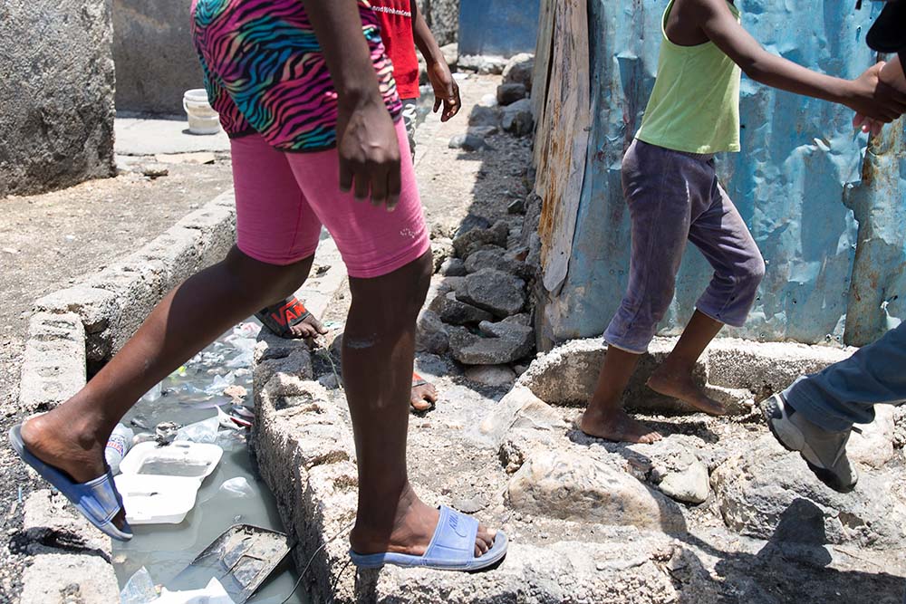 A family negotiates an open drain in Port au Prince Haiti