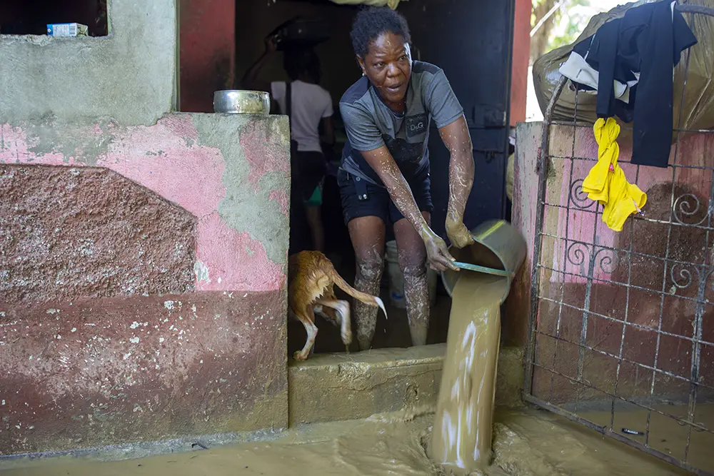 A Haitian woman bails flood water from her home