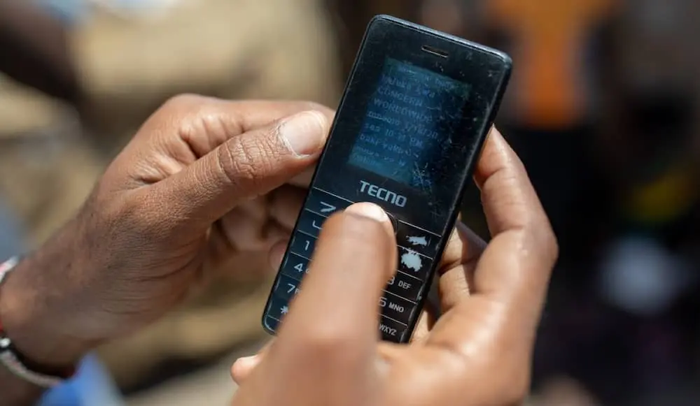 Closeup of someone holding a cell phone showing text of a received cash transfer.