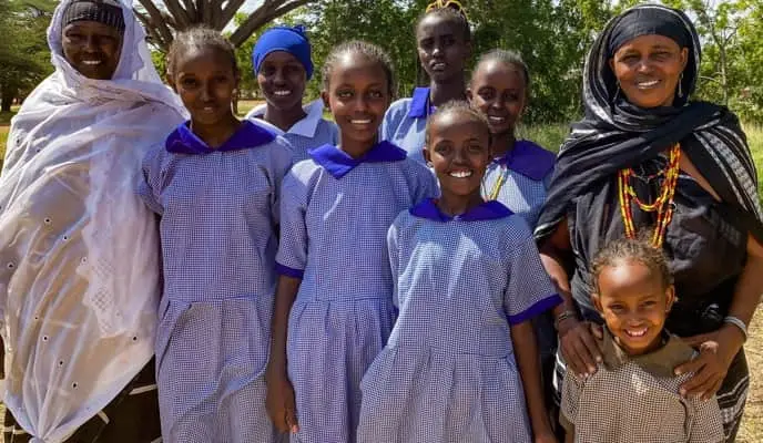 Two women posing with girls from the self help group they have supported in school