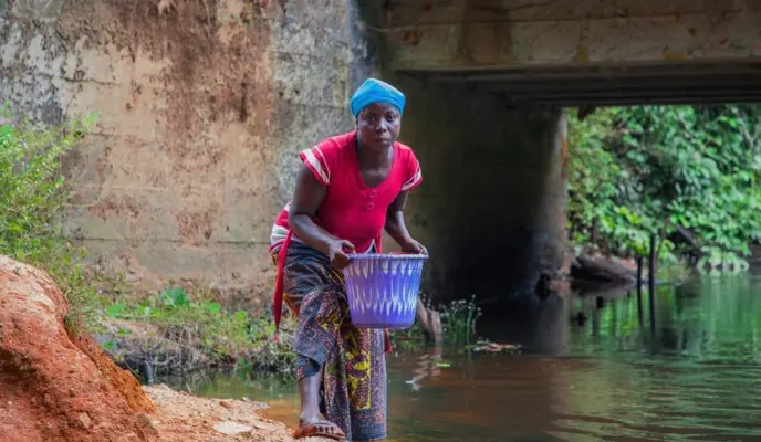 Liberian farmer Irene Togbah collects water from a local creek.