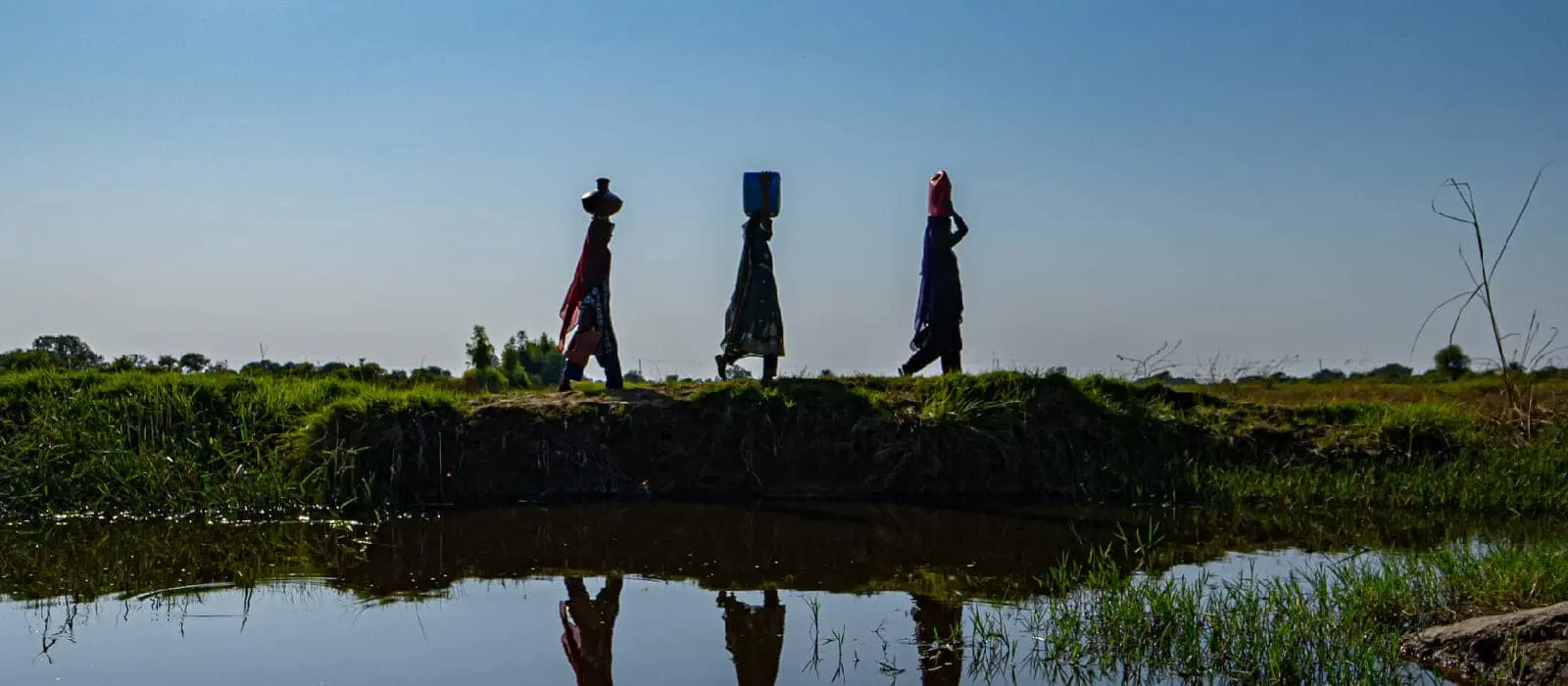 Women of the affected community on their way home carrying drinking water on their heads.