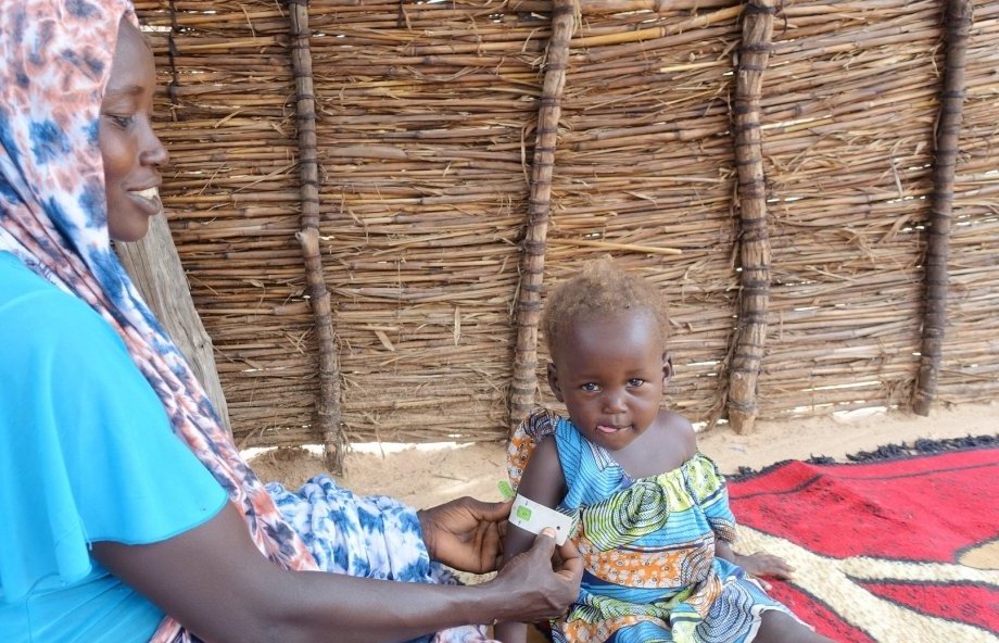 Khamissa, a community health volunteer, measures her baby's mid-upper arm circumference (MUAC) to chart her nutritional progress