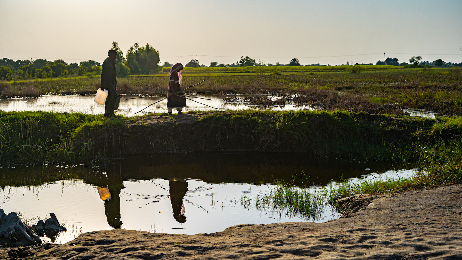 A father and daughter walk through the flooded area of Sindh Province with an emergency kit provided to them by Concern Worldwide during the 2022 Pakistan floods. (Photo: Ingenious Captures/Concern Worldwide)