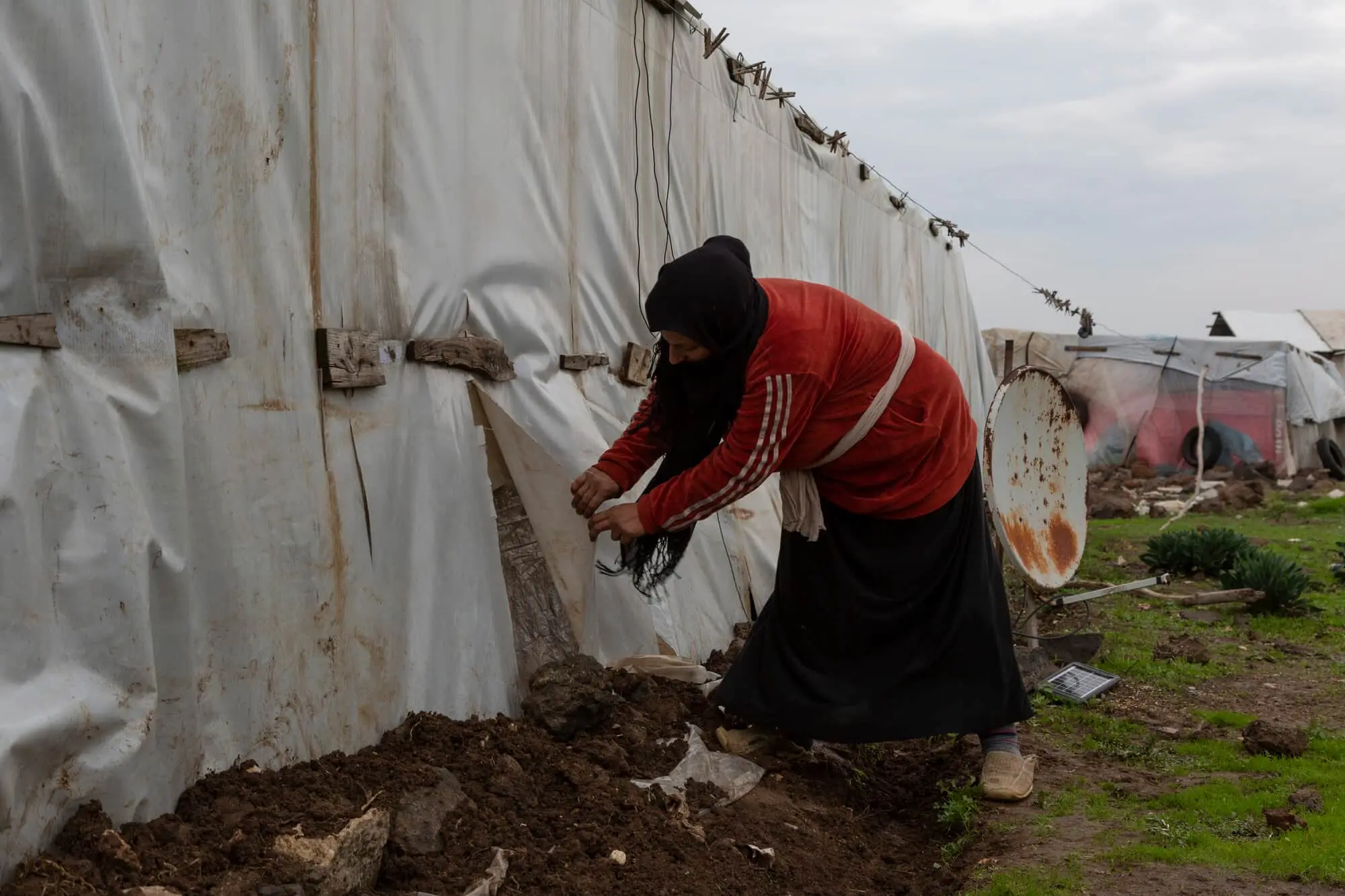 A Syrian refugee woman shows the torn plastic covers of her tent in the village of Shir Hmyrin, in Akkar.