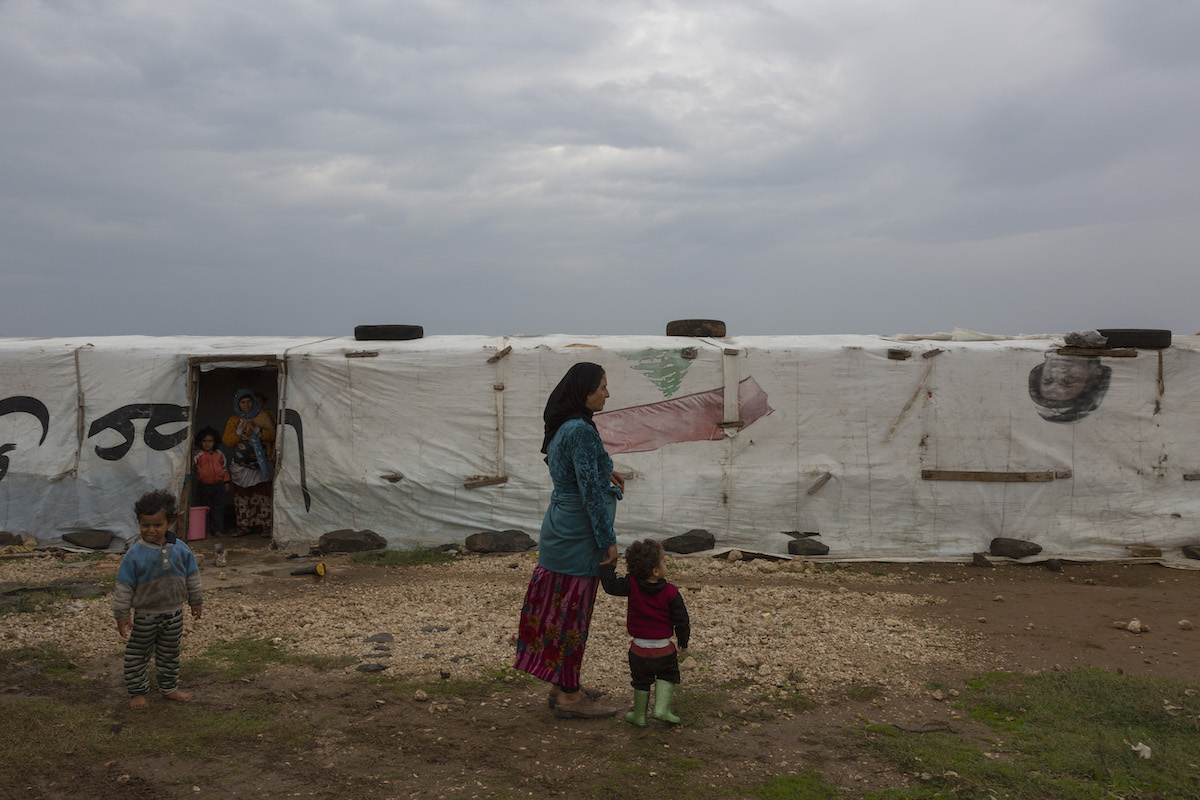 A Syrian refugee woman stands with her child in front of their tent in Lebanon. (Photo: Dalia Khamissy / Concern Worldwide)