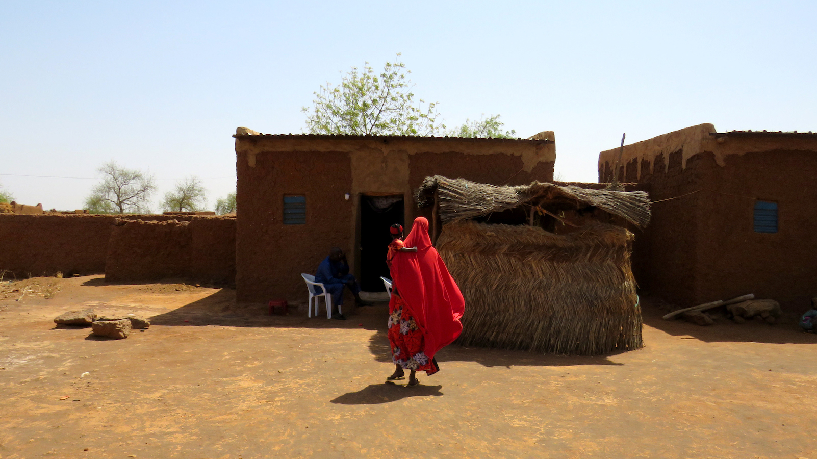 A Nigerien woman walks back towards her house with her back to the camera.