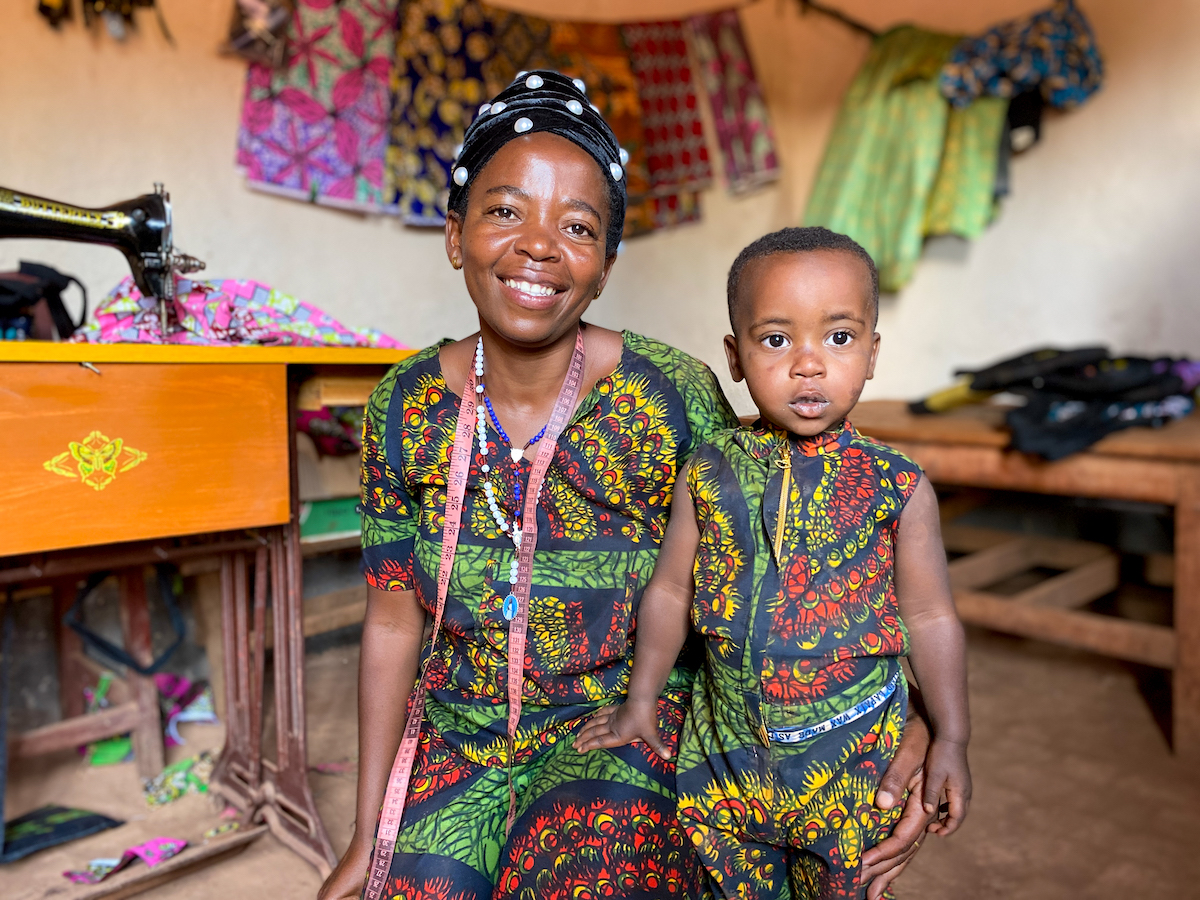 Alexia Mukashyaka (40) and her daughter Brigit (2) at her tailoring shop in Mugombwa, Gisagara. Alexia was selected for the Graduation Programme in 2019. After investing in a sewing machine, she started up a successful tailoring business, making on average 20 outfits for women each week. She plans to expand and eventually open a hairdressing salon, and is currently receiving lessons on hair styling. (Photo: Eugene Ikua/Concern Worldwide)