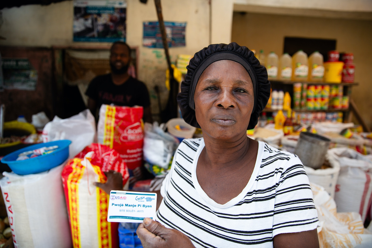 Estelle Adolphe, a participant in Manje Pi Byen uses her account to buy essential provisions from a vendor in Cité Soleil. (Photos: Kieran McConville/Concern Worldwide)