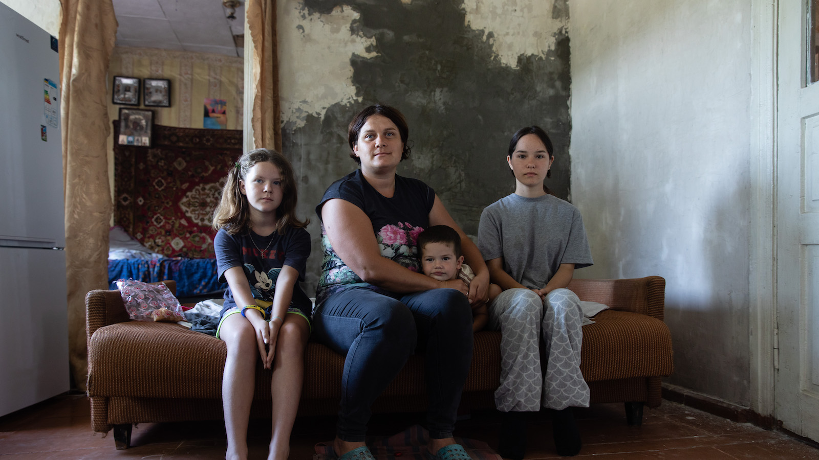 Internally-displaced Ukrainian Lesya* (33) with her three children in a house in Sumy Oblast where they were allowed to stay after the death of the owner. (Photo: Mykhaylo Palinchak/Concern Worldwide)