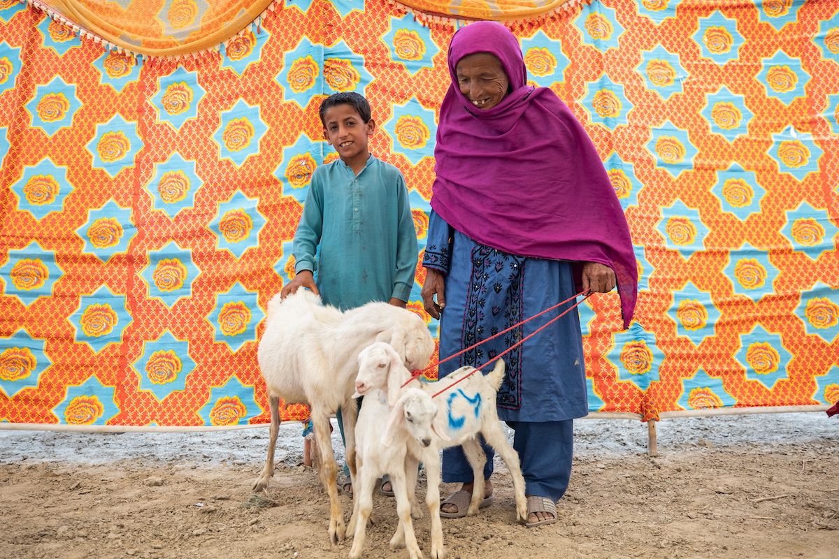 Khairi (80) and her grandson at a goat market in Sindh, Pakistan, facilitated by Concern. The market aims to help vulnerable women from flood-affected areas develop a sustainable business future via obtaining an asset that belongs solely to them. (Photo: Khaula Jamil/DEC)