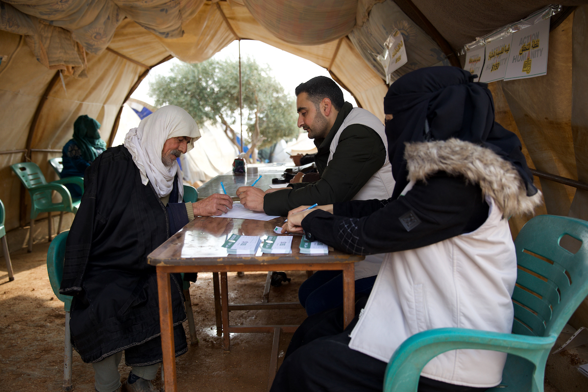 Omar* (66) receives a cash voucher distributed from Concern partner Syria Relief. Basil Kharouf and Ibtisam Al-Khanous help him fill out the necessary papers. (Photo: Ali Haj Suleiman/DEC/Fairpicture)