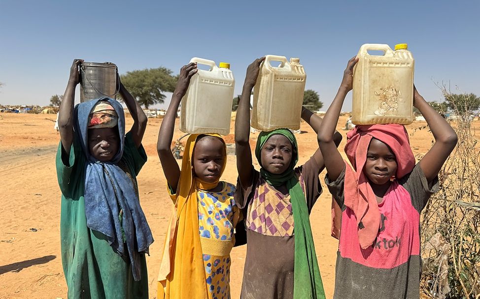 Children carry containers of water after filling them at a UNICEF borehole inside Adré refugee settlement in Chad. (Photo: Donaig Le Du/UNICEF)
