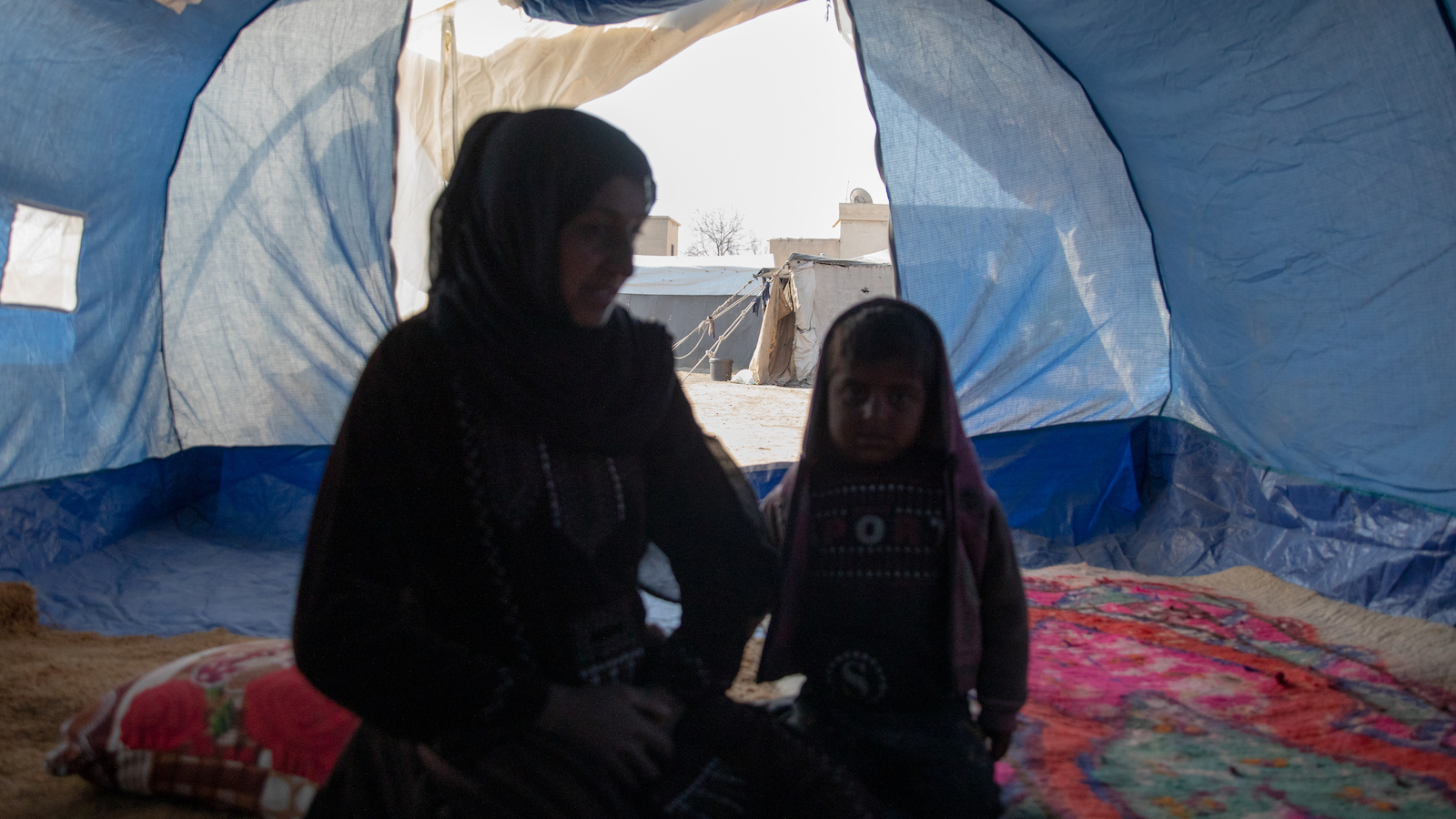 Amira* sits with her youngest child in a tent she calls home. She is one of the 11 million people who have been displaced within Syria over 15 years of conflict. (Photo: Gavin Douglas/Concern Worldwide)