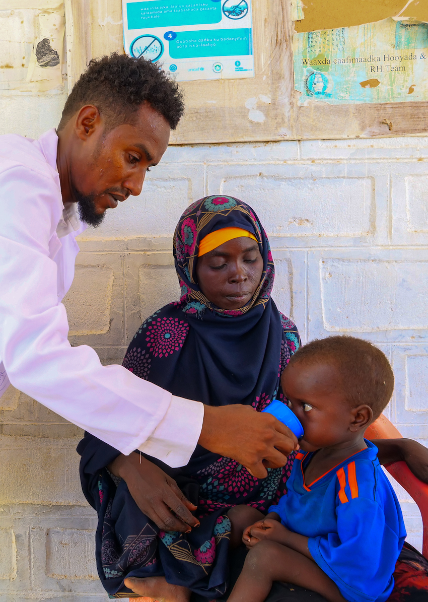 Ahmed Sahane Mohammed, nutritionist at West Imi Health centre provides supplementary food to Mubashir Dandiye(2) who had just been diagnosed with malnutrition. His mother Magol Abdulahi (32) looks on. Photo: Eugene Ikua/Concern Worldwide