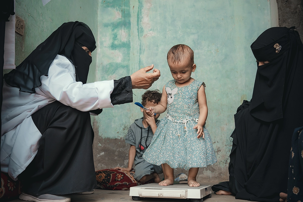 Rima* with her mother and Nabilah Mohammed, the Community Health Volunteer (CHV). Rima received treatment for malnutrition in a health center supported by Concern in Al-Shaqa’a village, Tuban district. (Photo: Ammar Khalaf/Concern Worldwide)