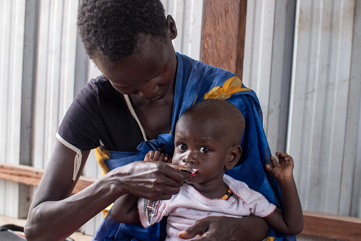 Nyapuoka Kai feeds her baby Nyayuach a packet of ready-to-use therapeutic food at an outpatient nutrition center in East Bentiu, South Sudan. (Photo: Jon Hozier-Bryne/Concern Worldwide)