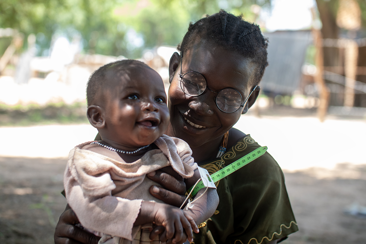 Alekiir and her daughter Achol wait outside a Concern nutrition center in Lueth Ngor, Northern Bahr el Ghazal State, South Sudan. While they wait, Alekiir measures Achol's mid-upper-arm circumference (MUAC) to check her nutrition levels. (Photo: Jon Hozier-Byrne/Concern Worldwide)