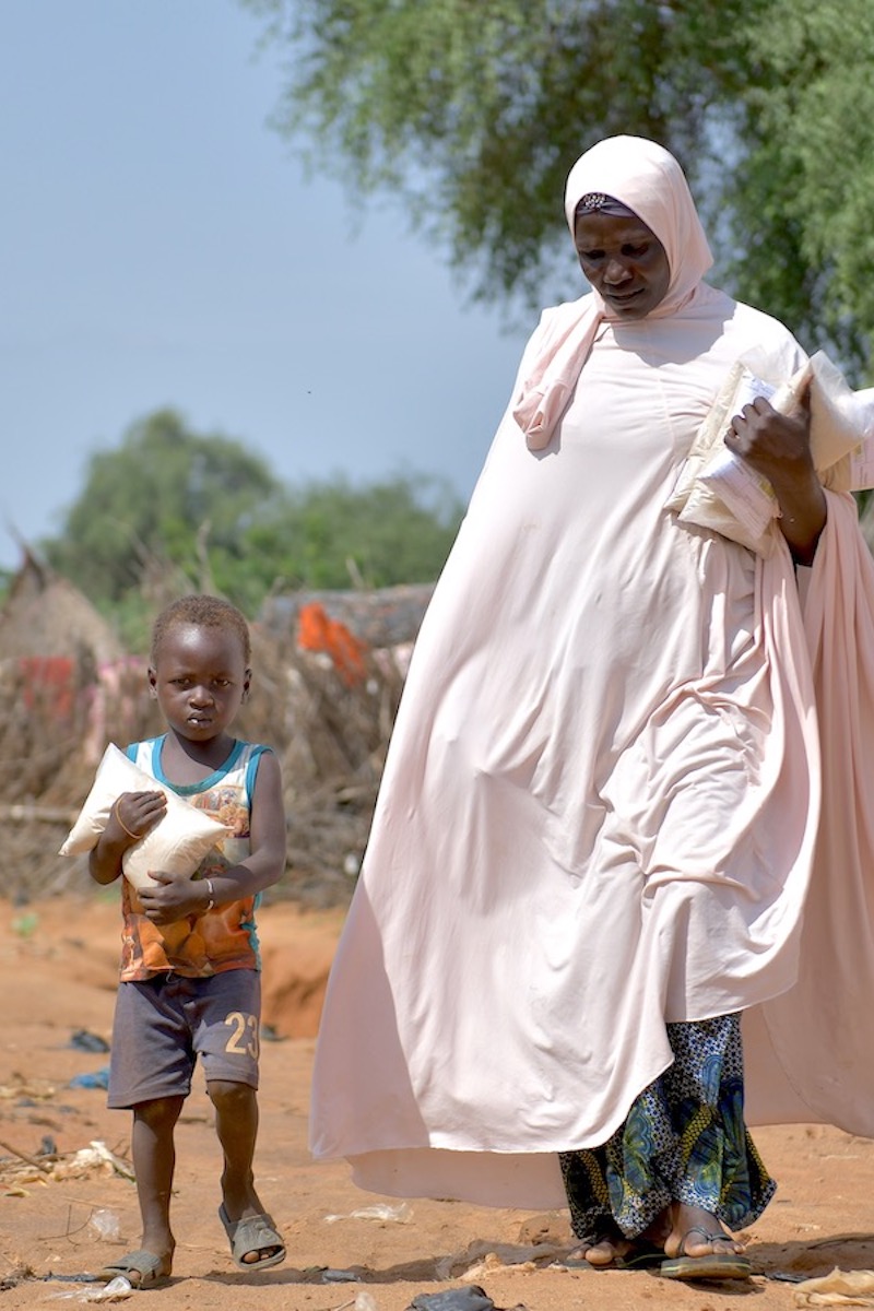 Baria Moumouni carries home packages of fortified flour with her child in Tanawara village. (Photo: Concern Worldwide)