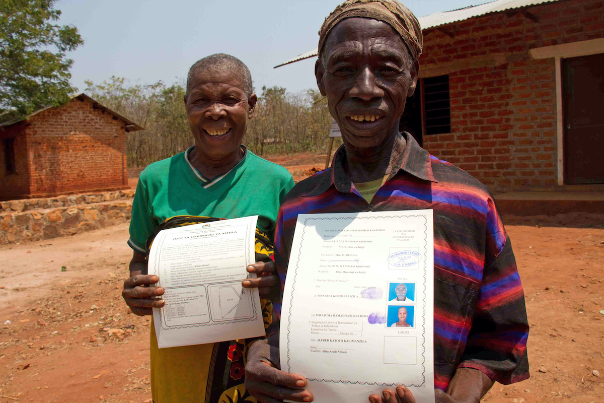 Village Chairperson, Paulo Christopher presenting Mustafa Kibibi Balizila and Mwajuma Ramadhani Kachira with their joint Land certificate in Kigoma Region, Tanzania. Photo: Jennifer O'Gorman/Concern Worldwide