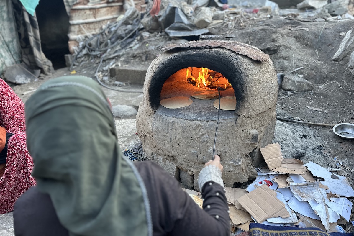 Manila* and her family were displaced to Rafah then to Al-Nuseirat in Gaza. She makes some bread with the resources they have, but they have no tent or access to food and water. (Photo: Khalil Adwan)