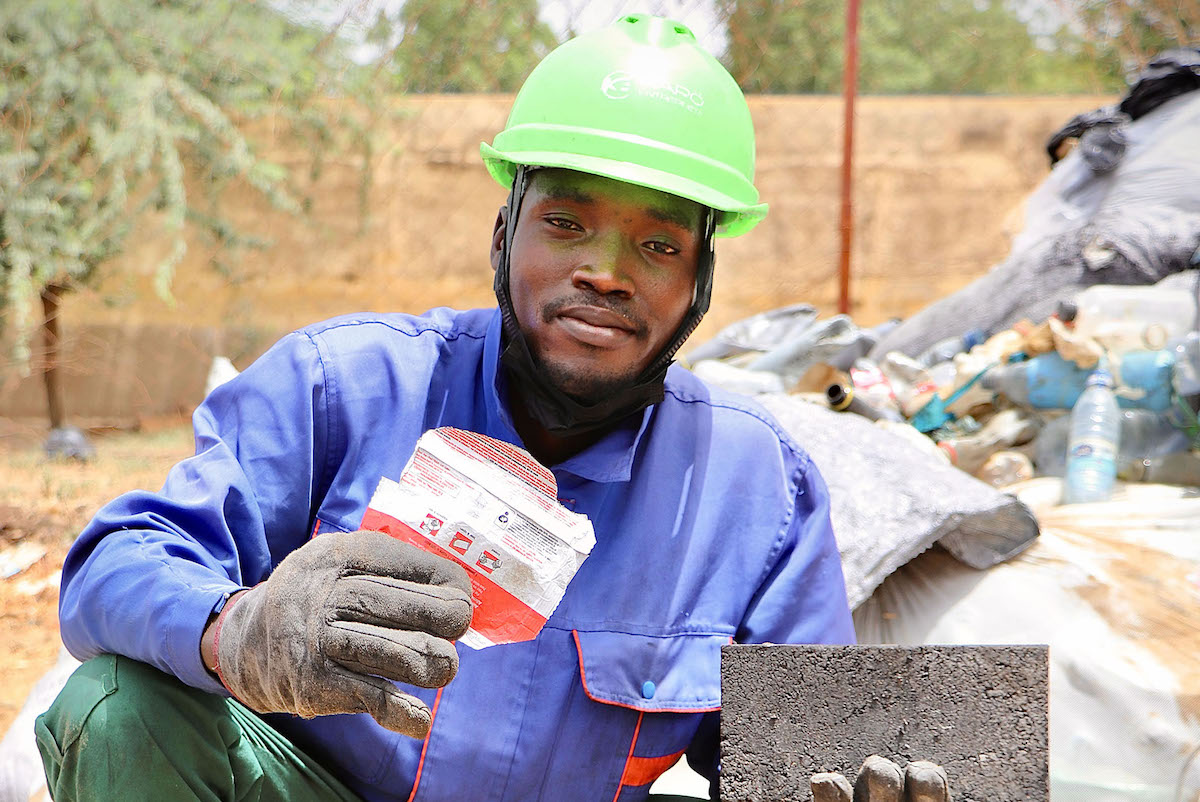 Karö Enterprise employee Maigao César holds an empty Plumpy’Nut (RUTF) packet collected from nutrition centres in Lake Chad. These packets, often discarded after use, are repurposed here as raw material for the production of eco-friendly bricks and paving stones, helping to reduce plastic pollution. (Photo: Pierre Maget/Concern Worldwide)