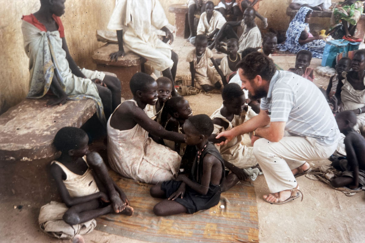 Concern Field Director Tom Lavin in southern Sudan, 1988, talking to civilians displaced by conflict waiting at a concern feeding center.