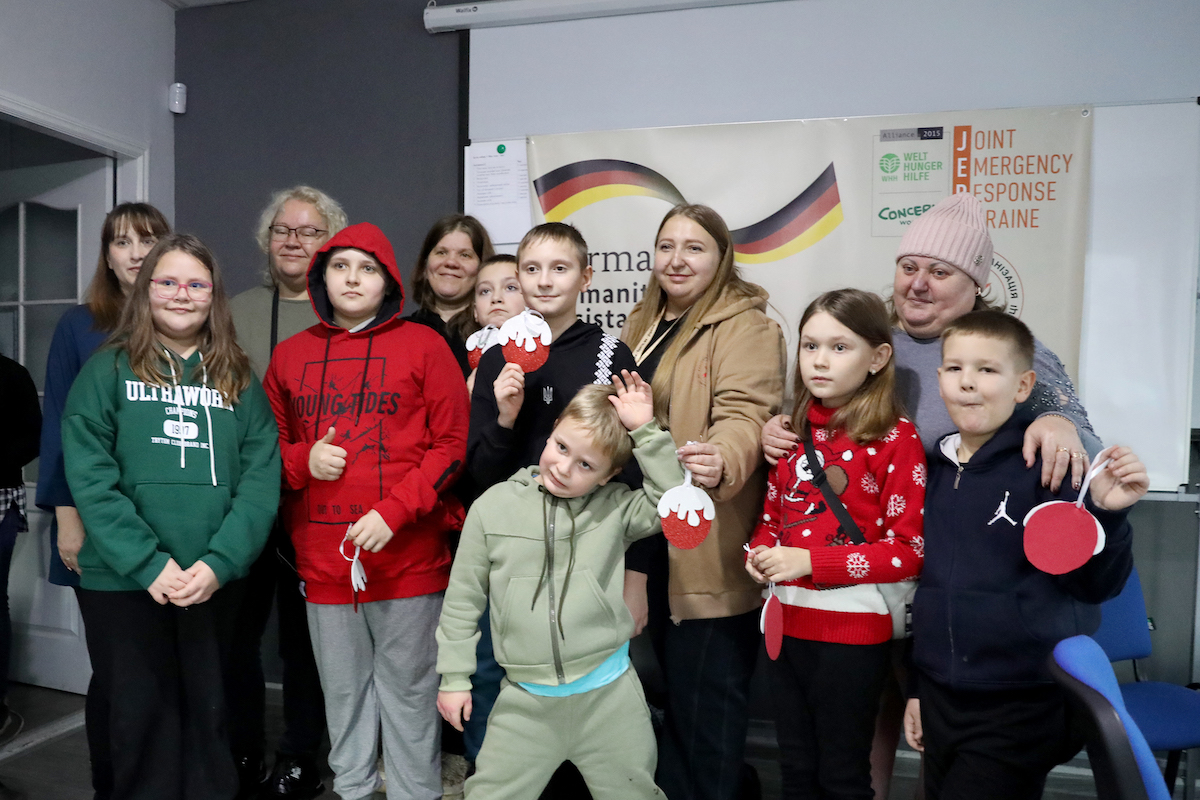 Yana* (right, in the red sweater) and Victoria* (behind her) with other members of the child-friendly PSS session led in Ukraine. They hold up new year's ball decorations. made as part of the session. (Photo: Jon Hozier-Byrne/Concern Worldwide)