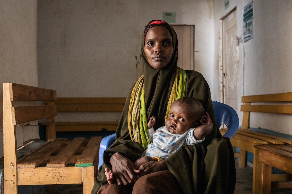 Kafeeyo* (23) holds her son Rahman* (8 months) in Siinka-Dheer Health Center. Concern's health and nutrition work in Somalia has been able to respond to rising hunger rates (and despite funding cuts) thanks to a grant from Coefficient Giving and GiveWell. (Photo: Ed Ram/Concern Worldwide)