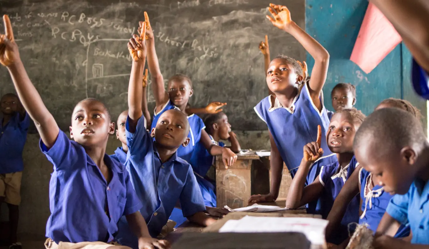 Children raise hands in classroom