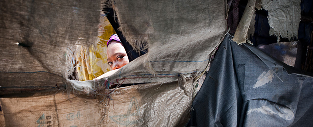 A woman peeks through a makeshift shelter