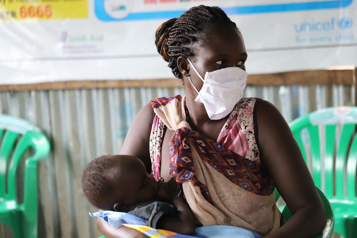 Nyaluit and Chudier wait at a Concern nutrition center to receive therapeutic food supplements. Nyaluit wears a mask to help prevent the spread of Covid-19. (Photo: Samir Bol / Concern Worldwide)