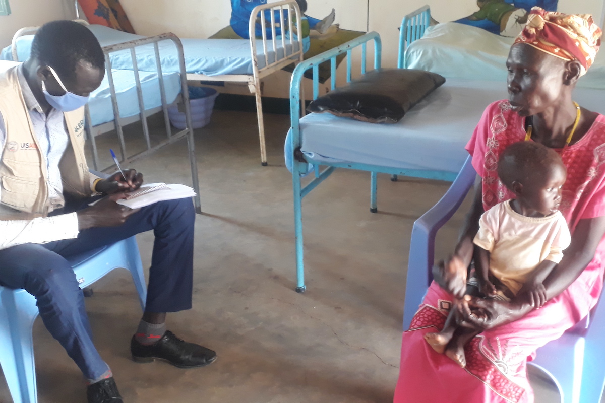 18 month old Abuk, is cared for by her grandmother Arek (65), who speaks with Concern Nutrition Officer Luka Malek. (Photo: Dominic Deng / Concern Worldwide)