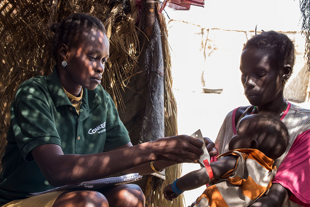 A Concern South Sudan nutrition worker screens a child for malnutrition by measuring her mid-upper arm circumference (MUAC).