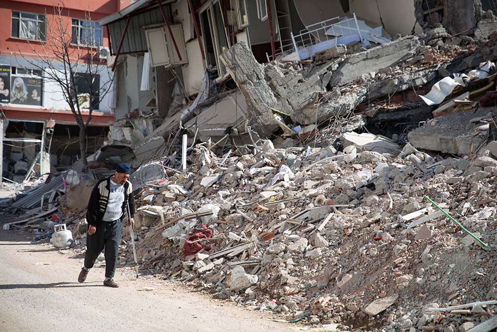 Man with crutch walks past collapsed building after Turkey earthquake
