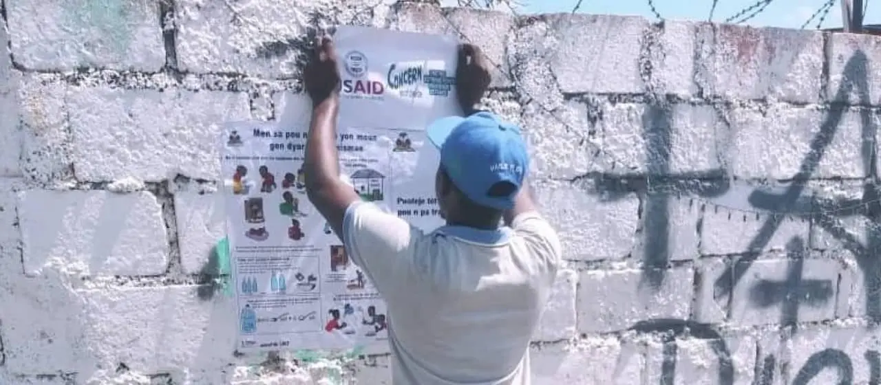 In Cité Soleil, Agents de Sante hang information posters as part of a response to the recent Cholera Outbreak.