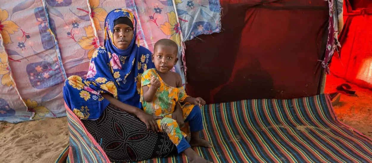 Woman with one of her children outside their hut in an IDP site on outskirts of Mogadishu.