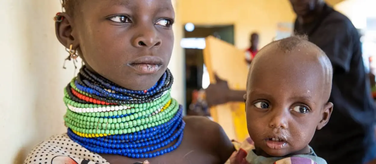 Girl holds her younger sister as they wait to be screened for malnutrition at Sasame Dispensary, Kibish North in Kenya's Turkana province.