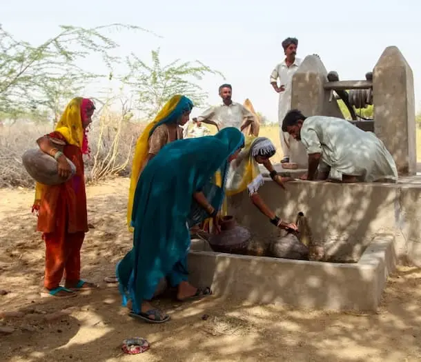 Women fetch water at a dug well