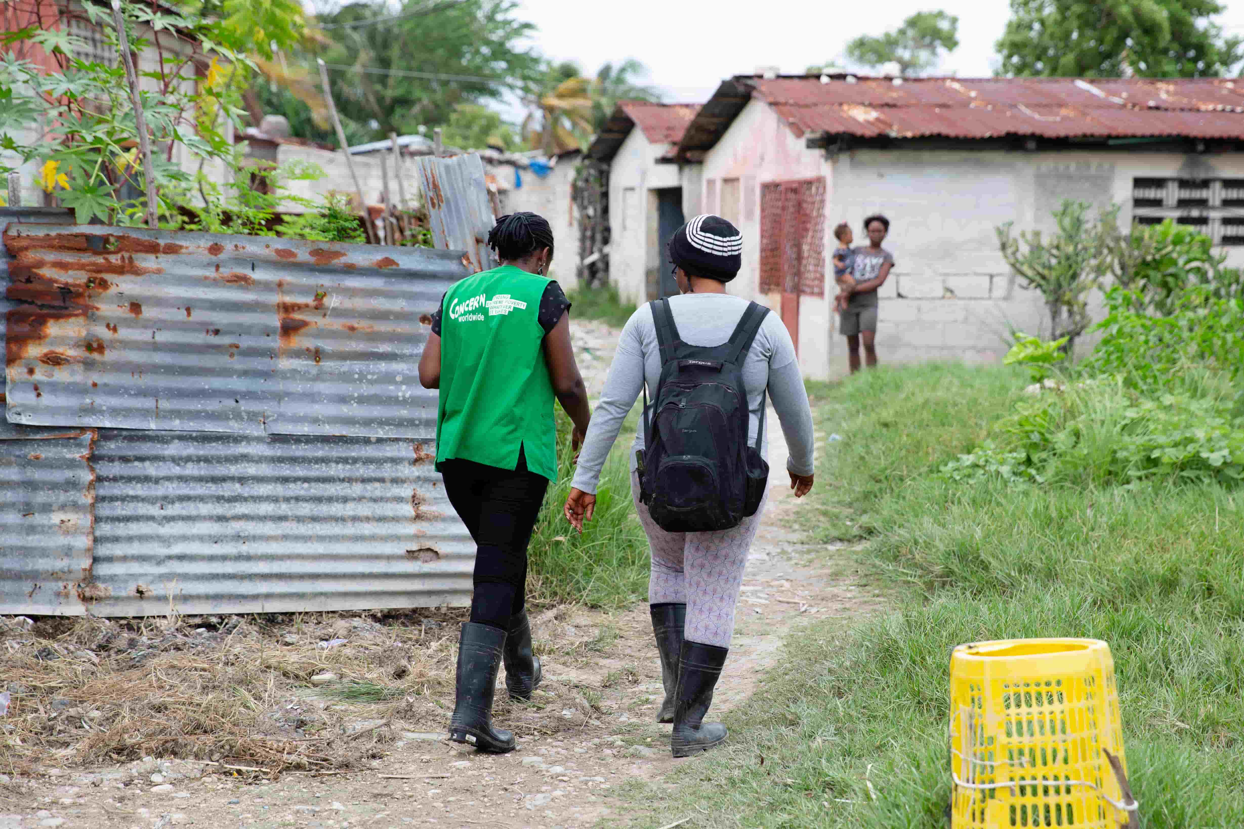 Concern staff and project participant walk on dirt path in Haiti.